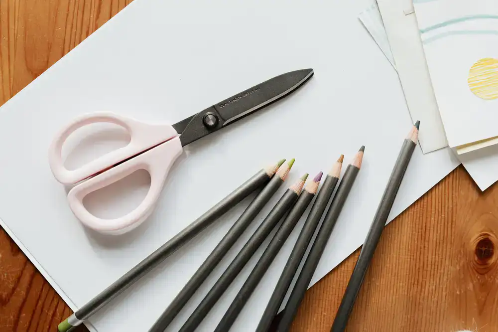 Overhead view of an artisan studio table with paper, scissors, and ribbons